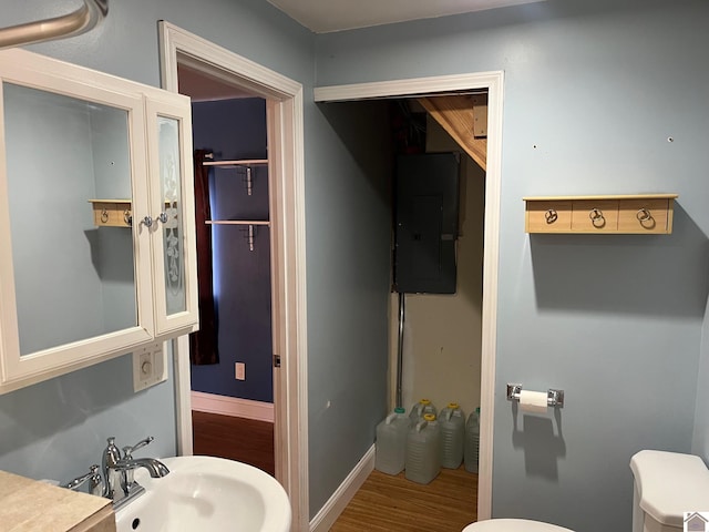 bathroom with toilet, wood-type flooring, sink, and electric panel