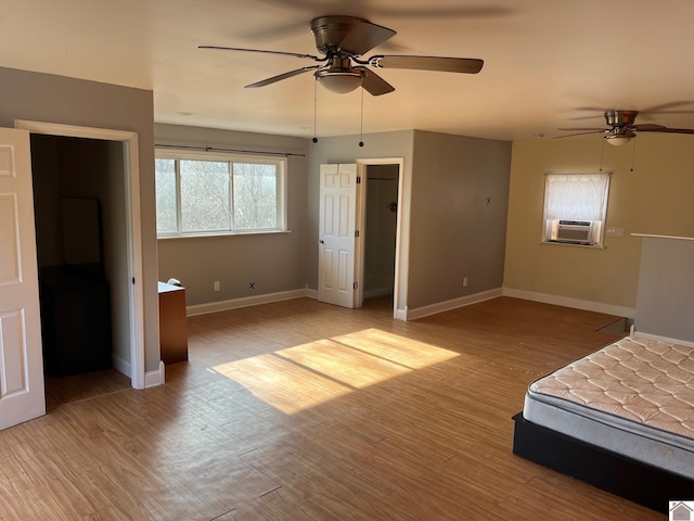 unfurnished bedroom with ceiling fan, light hardwood / wood-style flooring, cooling unit, and a spacious closet