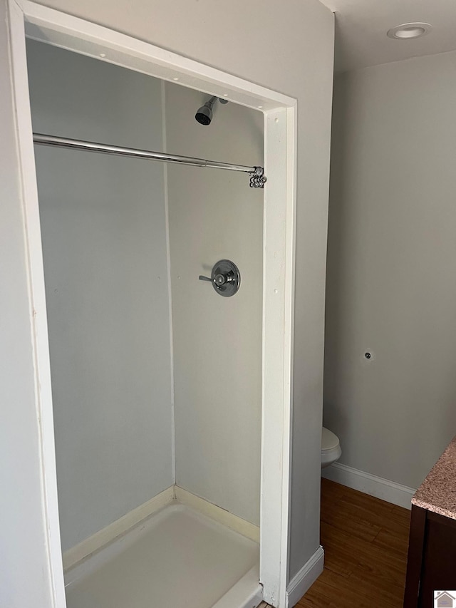 bathroom featuring a shower, wood-type flooring, and toilet