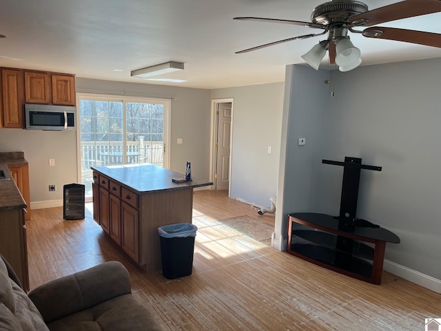 kitchen featuring ceiling fan, a center island, and light hardwood / wood-style floors