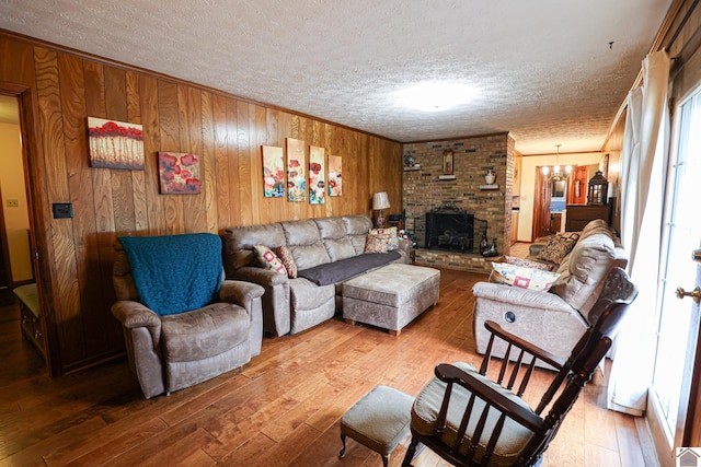 living room with wood walls, a chandelier, a textured ceiling, and hardwood / wood-style flooring