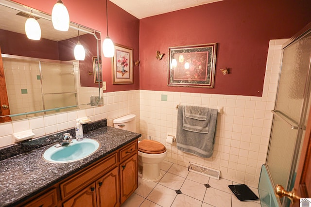 bathroom with tile patterned flooring, a shower with shower door, tile walls, and toilet