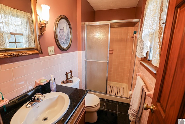 bathroom with tile walls, vanity, an enclosed shower, and toilet