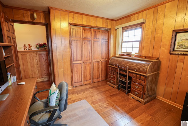 office area featuring light hardwood / wood-style floors, a textured ceiling, and wooden walls