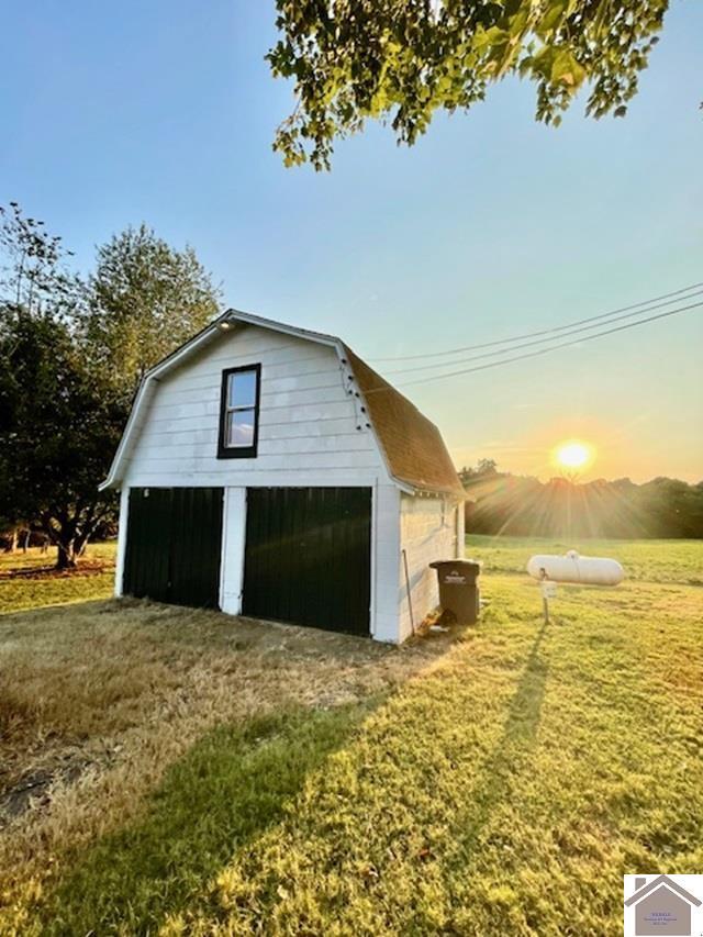 garage at dusk featuring a lawn