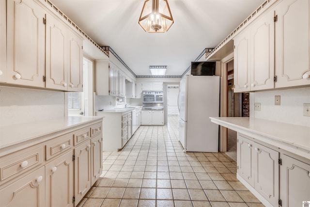 kitchen with white fridge, light tile patterned flooring, a healthy amount of sunlight, and a chandelier