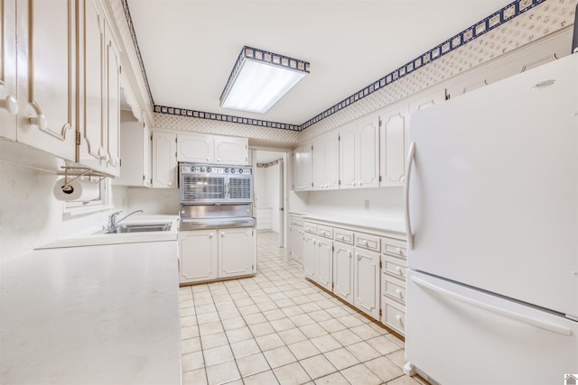 kitchen with white cabinets, oven, white refrigerator, and sink