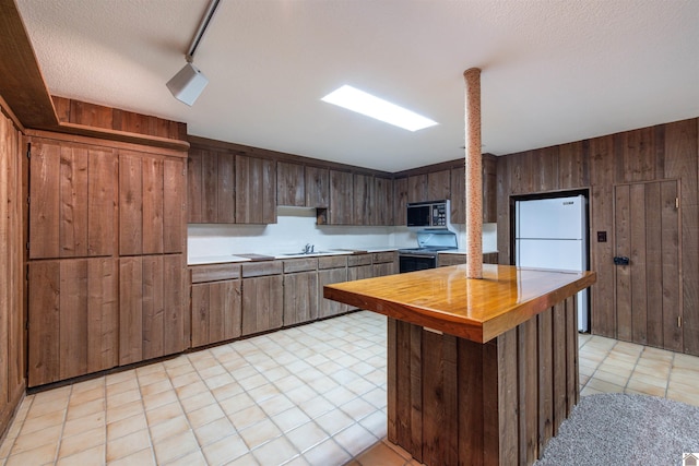 kitchen with a textured ceiling, black range with electric cooktop, dark brown cabinetry, wooden walls, and white refrigerator