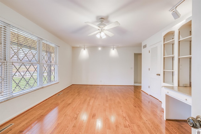 empty room with light wood-type flooring, rail lighting, and ceiling fan