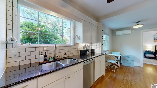 kitchen featuring backsplash, white cabinetry, stainless steel dishwasher, and light hardwood / wood-style floors