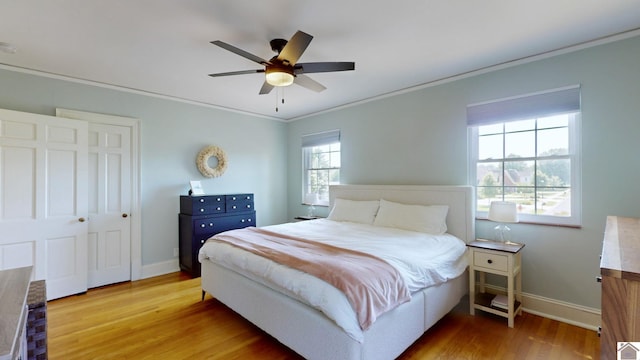 bedroom with hardwood / wood-style floors, multiple windows, ornamental molding, and ceiling fan