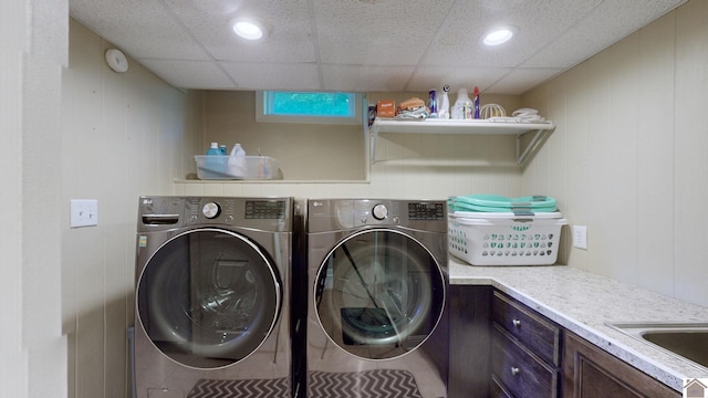 clothes washing area featuring wooden walls, cabinets, and independent washer and dryer