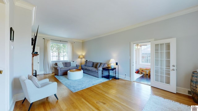 living room with light wood-type flooring, ceiling fan, and crown molding