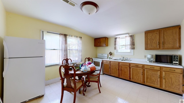 kitchen with white appliances, lofted ceiling, and sink