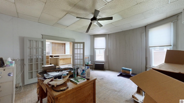 office with wood walls, radiator, french doors, ceiling fan, and light parquet flooring