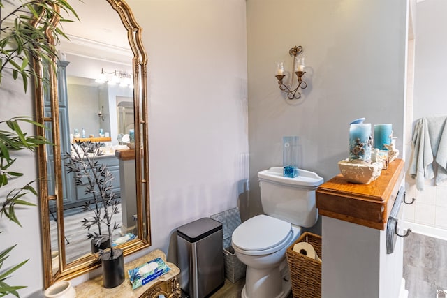 bathroom featuring toilet, ornamental molding, and hardwood / wood-style flooring