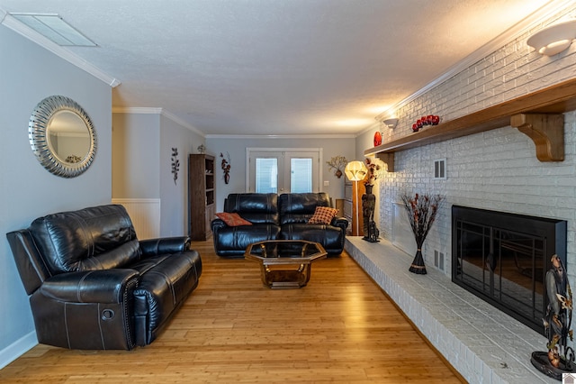 living room with a brick fireplace, light hardwood / wood-style flooring, brick wall, and ornamental molding