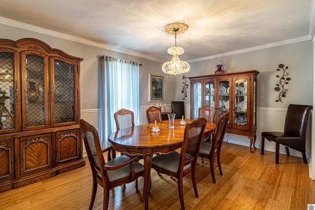 dining room featuring a chandelier, wooden walls, light hardwood / wood-style flooring, and ornamental molding