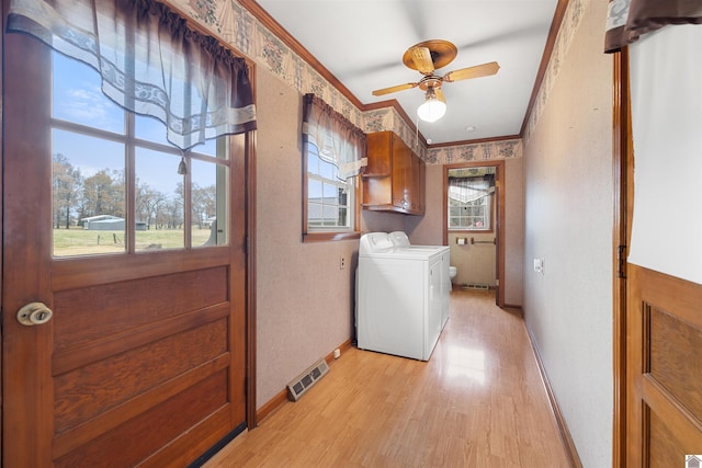 laundry area featuring cabinets, crown molding, light hardwood / wood-style flooring, ceiling fan, and washing machine and clothes dryer