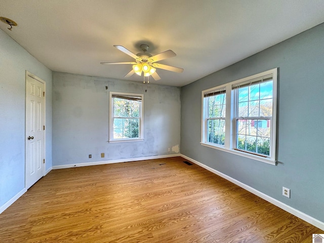 spare room featuring a wealth of natural light, light hardwood / wood-style flooring, and ceiling fan