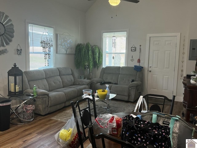 living room with hardwood / wood-style floors, ceiling fan, electric panel, and vaulted ceiling