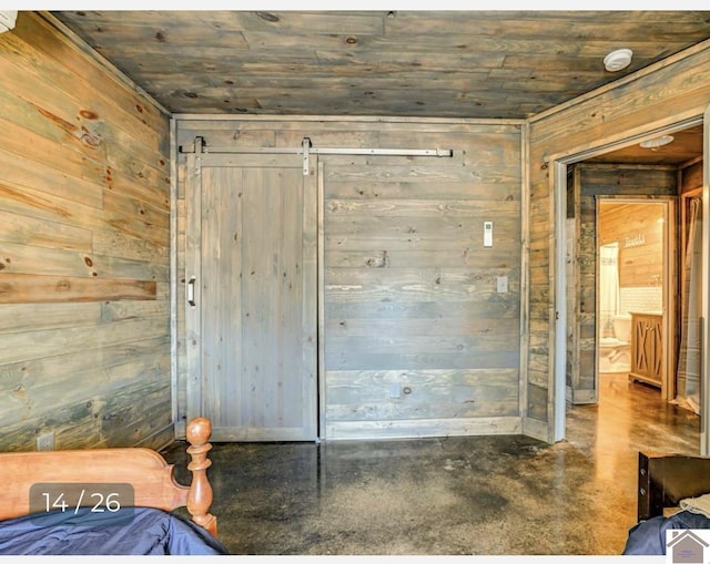 bedroom featuring a barn door, concrete floors, wooden ceiling, and wood walls