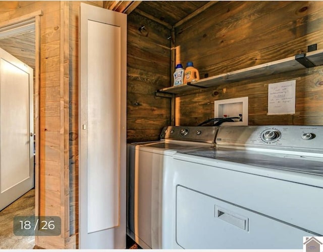 clothes washing area with washing machine and dryer and wooden walls