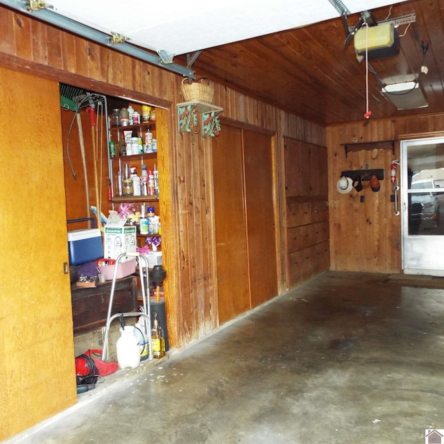 garage featuring a garage door opener and wooden walls