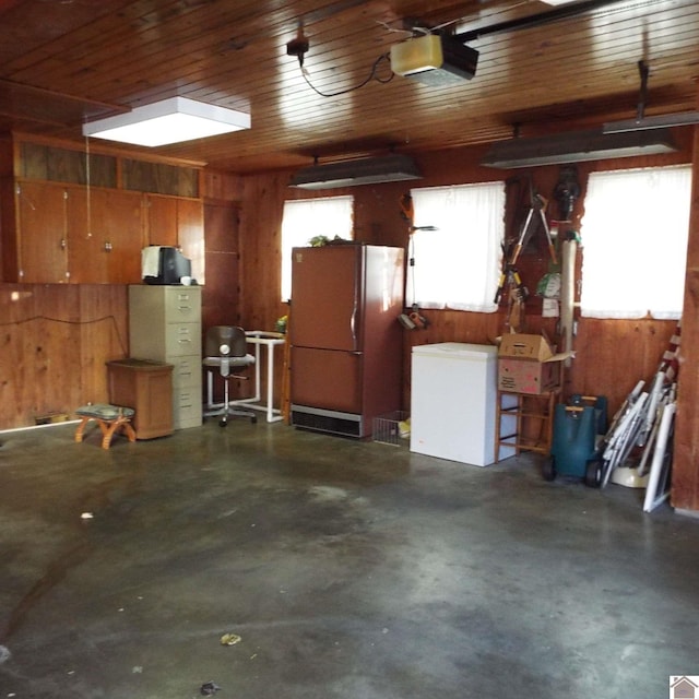 garage with refrigerator, white fridge, a garage door opener, and wooden walls