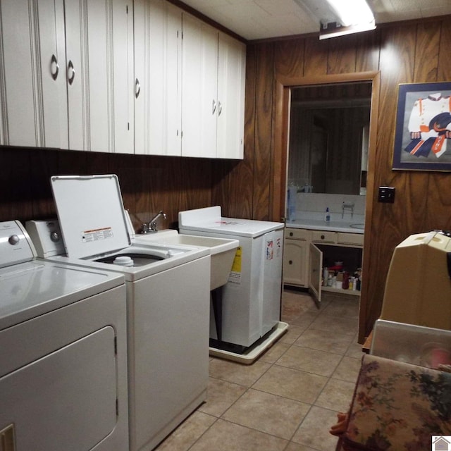 laundry area with wood walls, cabinets, independent washer and dryer, and light tile patterned flooring