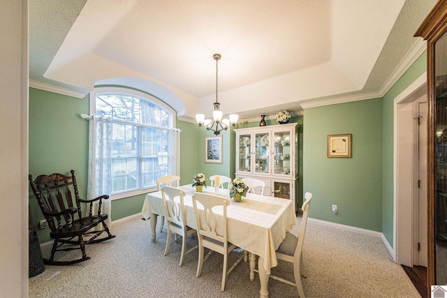 carpeted dining area with an inviting chandelier, crown molding, and a tray ceiling