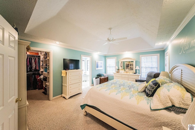 carpeted bedroom featuring a textured ceiling, a spacious closet, ceiling fan, and ornamental molding