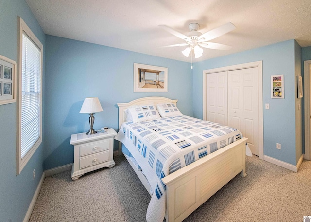 carpeted bedroom with ceiling fan, a textured ceiling, and a closet