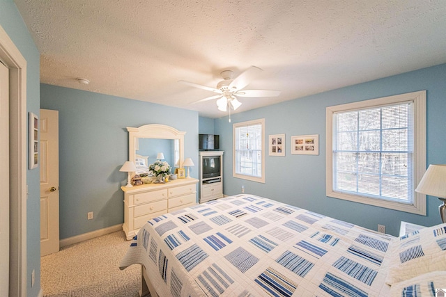 bedroom featuring ceiling fan, light colored carpet, and a textured ceiling