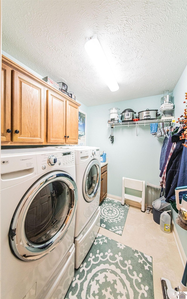 laundry room with cabinets, a textured ceiling, and washing machine and clothes dryer