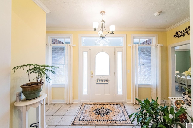 tiled foyer entrance featuring a textured ceiling, a notable chandelier, and crown molding