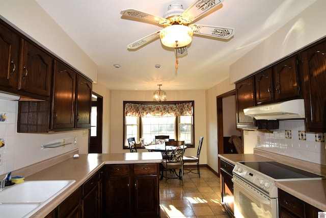 kitchen with ceiling fan with notable chandelier, sink, hanging light fixtures, electric range, and kitchen peninsula