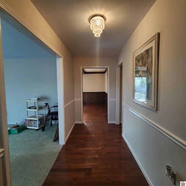 corridor featuring a chandelier and dark colored carpet