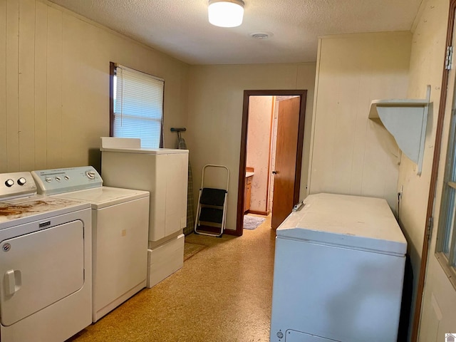 laundry area featuring separate washer and dryer, a textured ceiling, and wooden walls