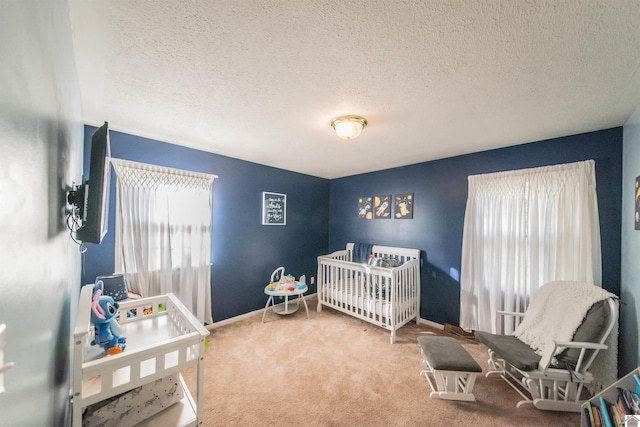 bedroom featuring a crib, carpet, and a textured ceiling