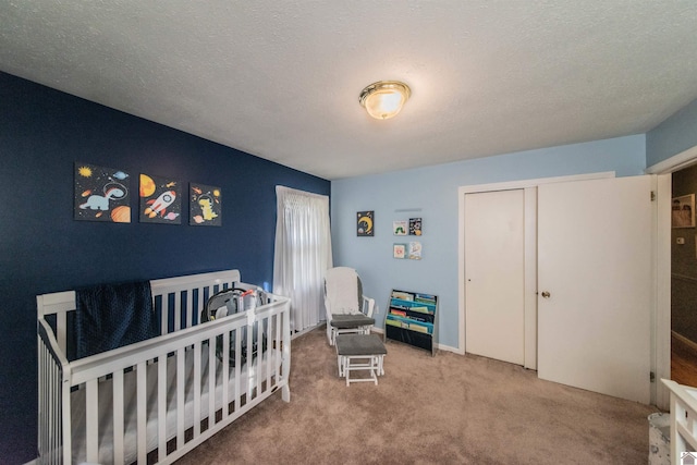 carpeted bedroom with a closet, a nursery area, and a textured ceiling