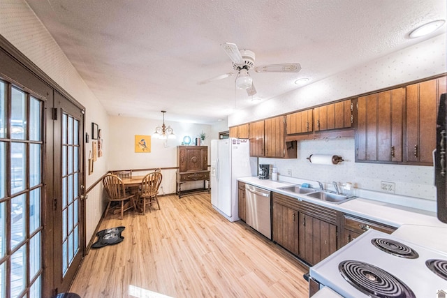 kitchen featuring white appliances, sink, hanging light fixtures, light wood-type flooring, and a textured ceiling