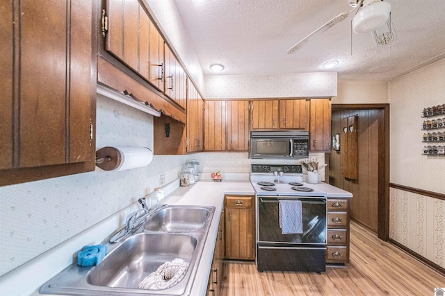 kitchen featuring a textured ceiling, light hardwood / wood-style flooring, white range with electric cooktop, and sink