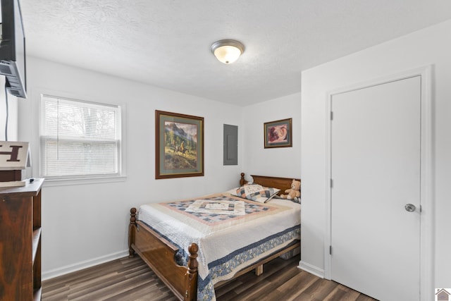 bedroom with a textured ceiling, dark wood-type flooring, and electric panel