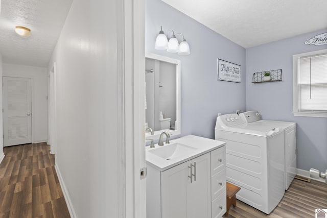 bathroom with hardwood / wood-style floors, vanity, toilet, washing machine and dryer, and a textured ceiling