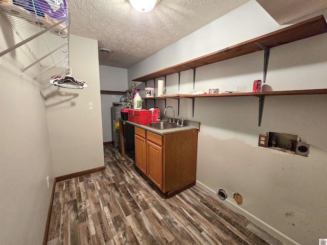 laundry area with dark wood-style flooring, washer hookup, a sink, hookup for an electric dryer, and cabinet space