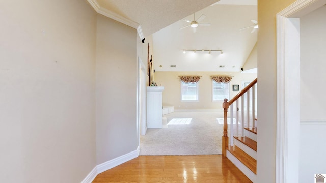 hall featuring a textured ceiling, rail lighting, vaulted ceiling, and light wood-type flooring