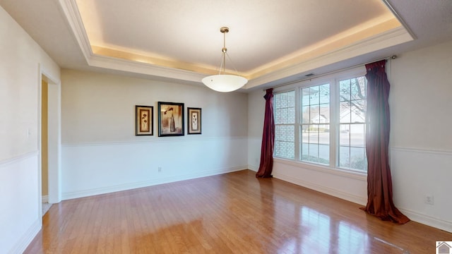 unfurnished room featuring light wood-type flooring and a tray ceiling