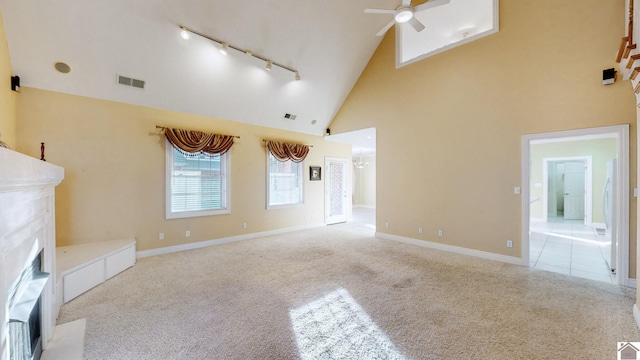 unfurnished living room with rail lighting, light colored carpet, high vaulted ceiling, and ceiling fan