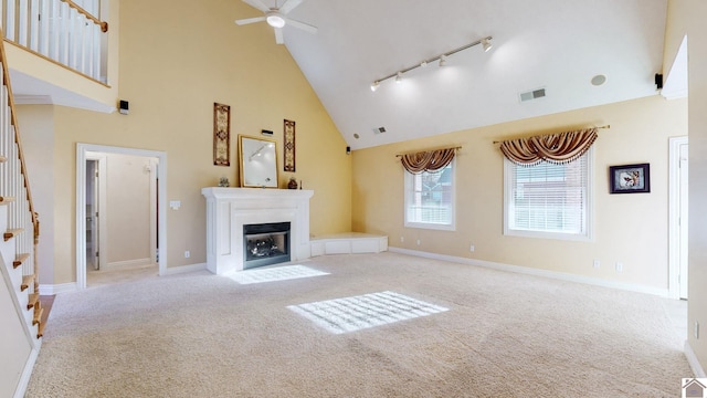 unfurnished living room featuring track lighting, light colored carpet, high vaulted ceiling, and ceiling fan